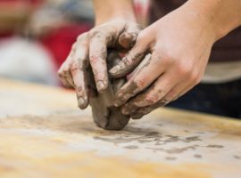 two hands shaping clay