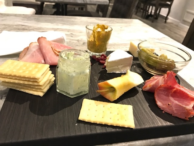 black tray with crackers and sliced meats an apple core