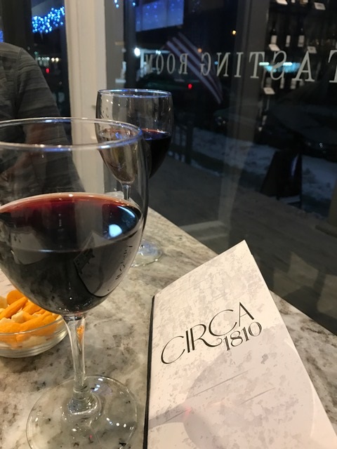 glass half full of red wine sitting next to menu titled Circa 1810