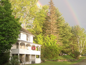 House with two story exterior porch with trees in the background