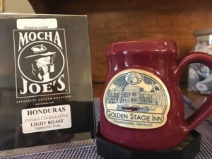 red pottery mugh sitting on table next to table top sign announcing Mocha joe's coffee