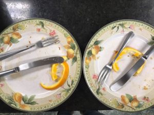 two plates, each with knife and fork and empty orange rind and leftover pancake crumbs