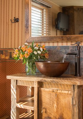 wood table with bronze bowl being filled with water from hand pump